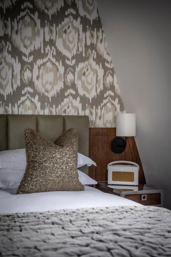 The Marylebone Hotel Londra Esterno foto A bedroom with a bed, a nightstand, a lamp, and a pillow